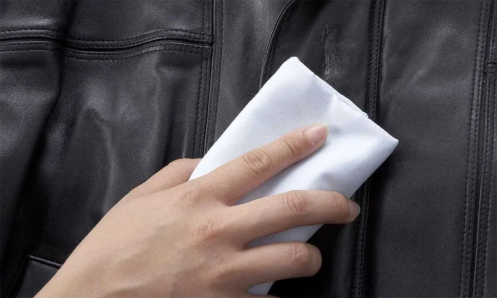 wiping black leather jacket with cloth