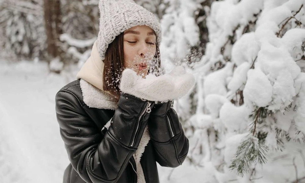 woman blowing snow in black leather jacket