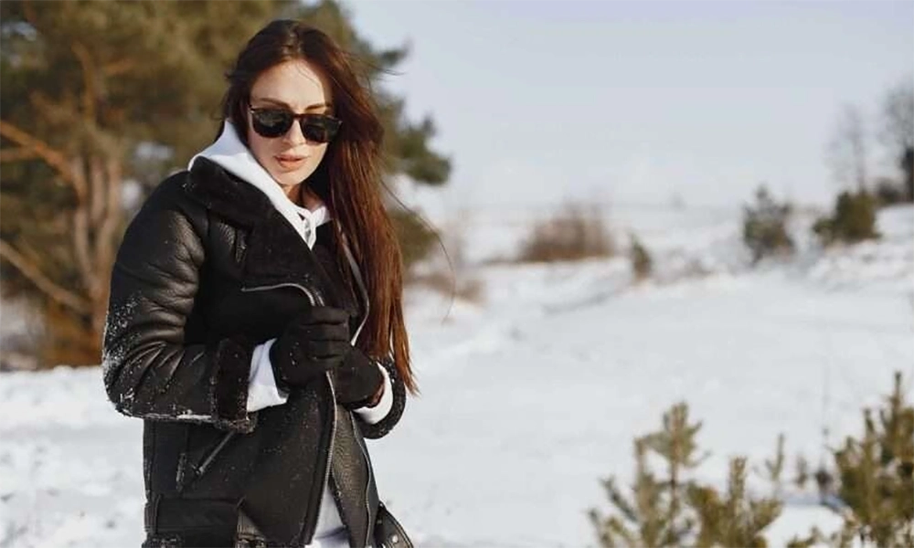 woman in black leather shearling jacket in snow